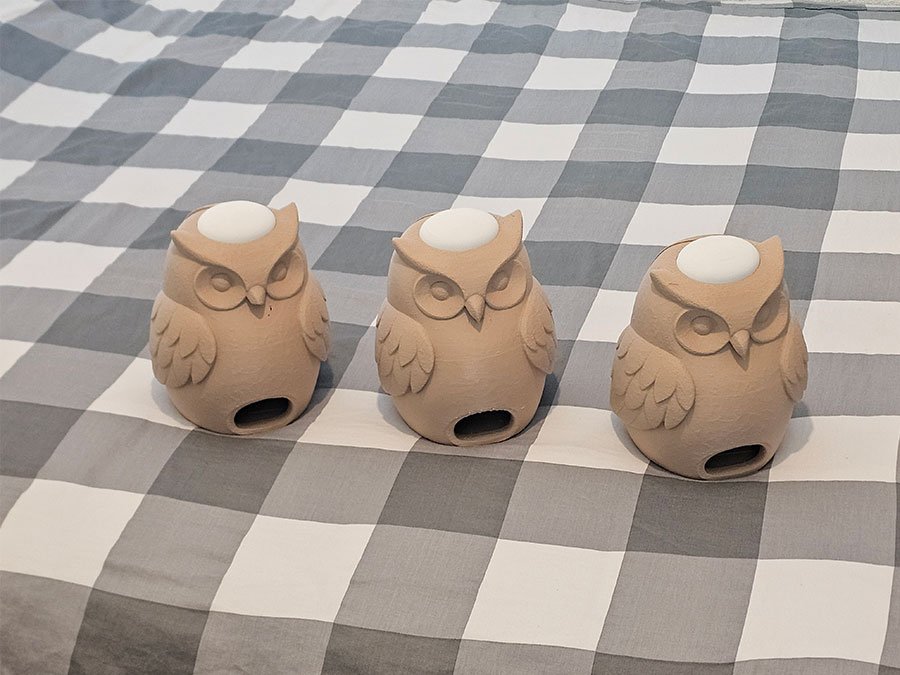 Trois hiboux beiges imprimés en 3D, avec une ouverture ronde sur le dessus