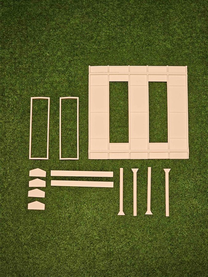 Éléments de façade miniature à assembler, alignés sur un fond vert
