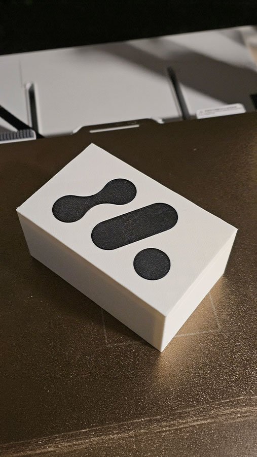 Moule rectangulaire blanc imprimé en 3D, avec trois formes noires sur la face supérieure